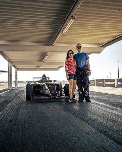 happy couple in front of Formula 4 car