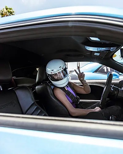 student in car, holding up peace sign